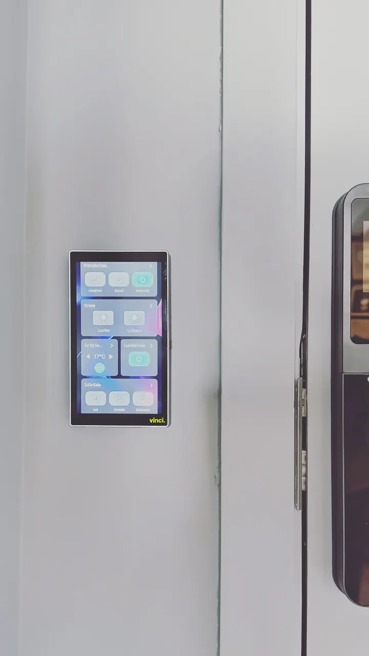Painel touch na parede com botões de luz, cenas e ar-condicionado, ao lado de uma porta com fechadura digital.