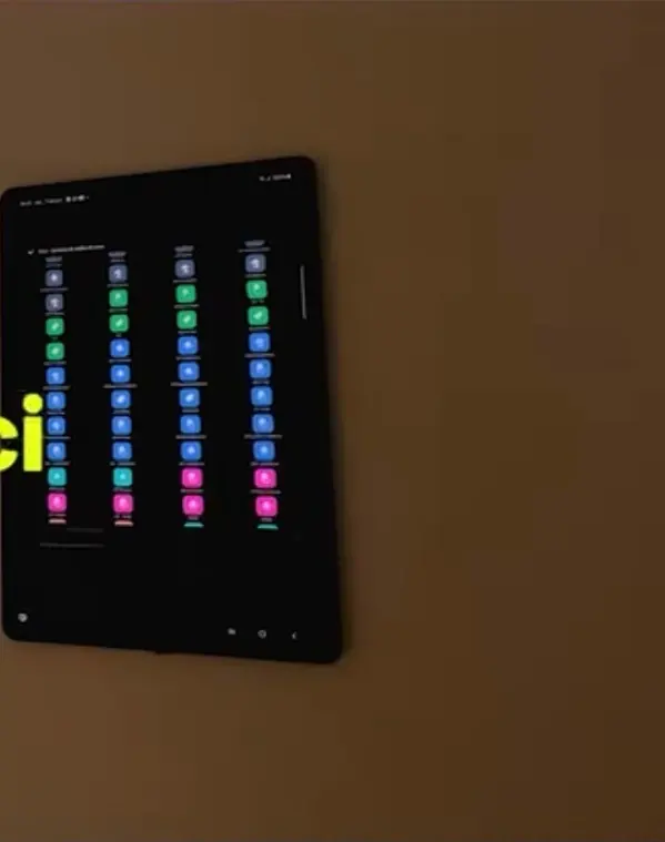 Tablet preso na parede com colunas de botões coloridos de cenas.