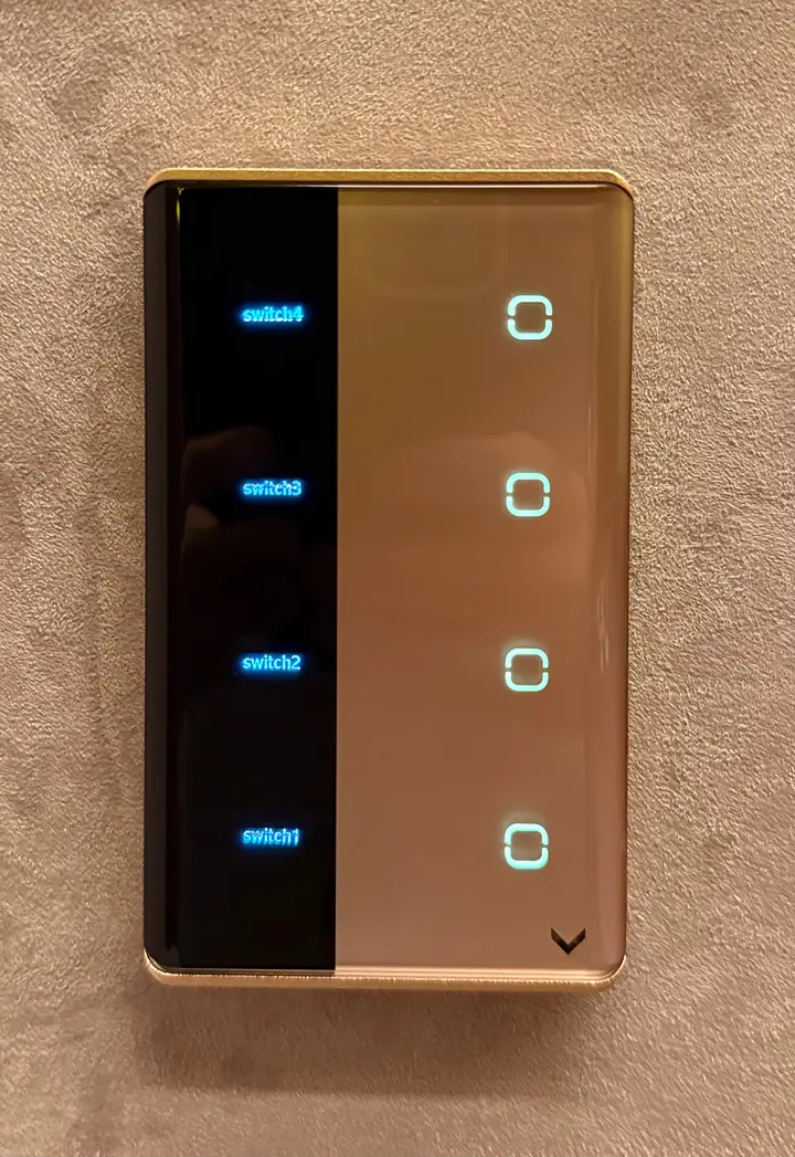 Interruptor touch de vidro champanhe com faixa preta de legendas iluminadas, em parede de textura bege.