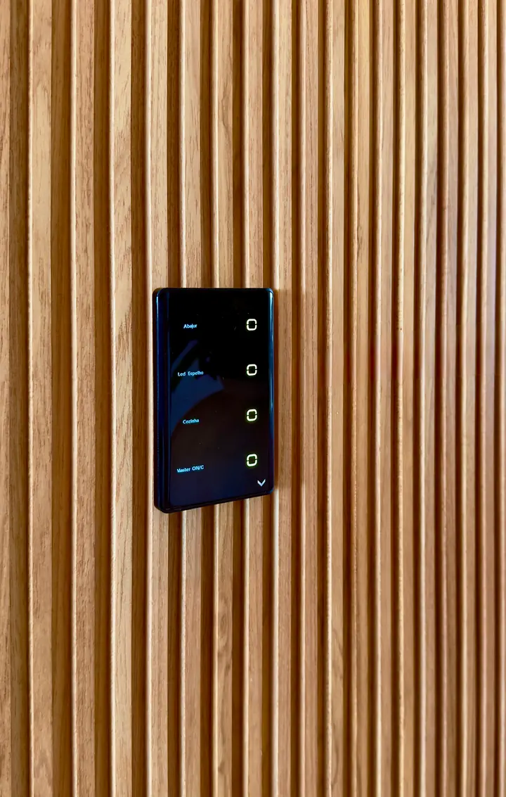 Interruptor touch de vidro preto com as teclas Abajur, Led Espelho, Cozinha e Master, em parede de ripado de madeira.